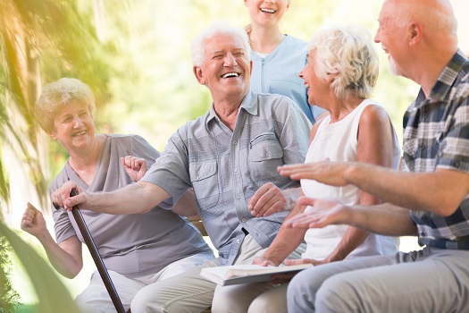 picture of elderly people sitting on a bench in a park and laughing and enjoying themselves
